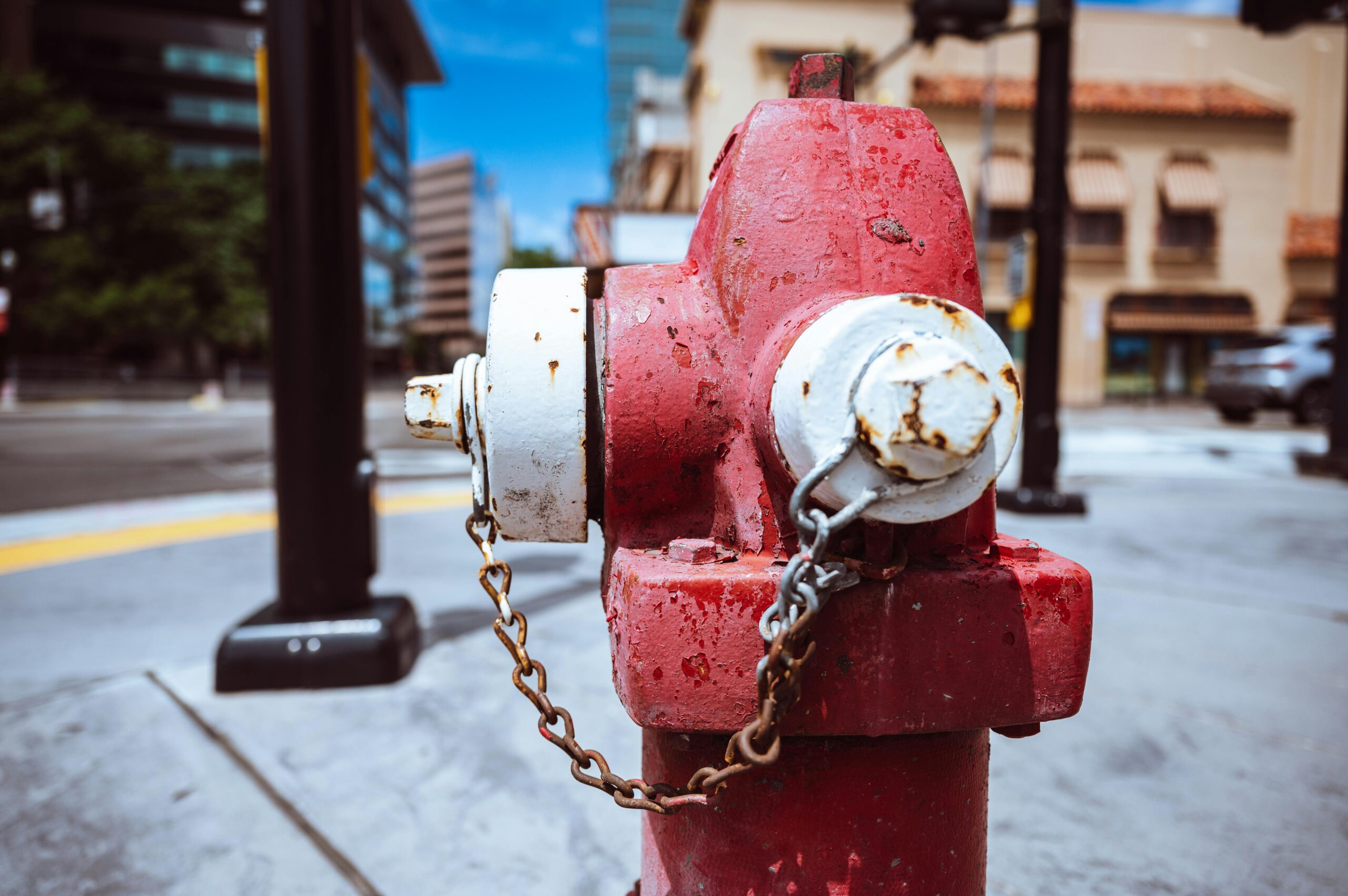 Typical red fire hydrant with rusty chain located on roadside in modern city on sunny day