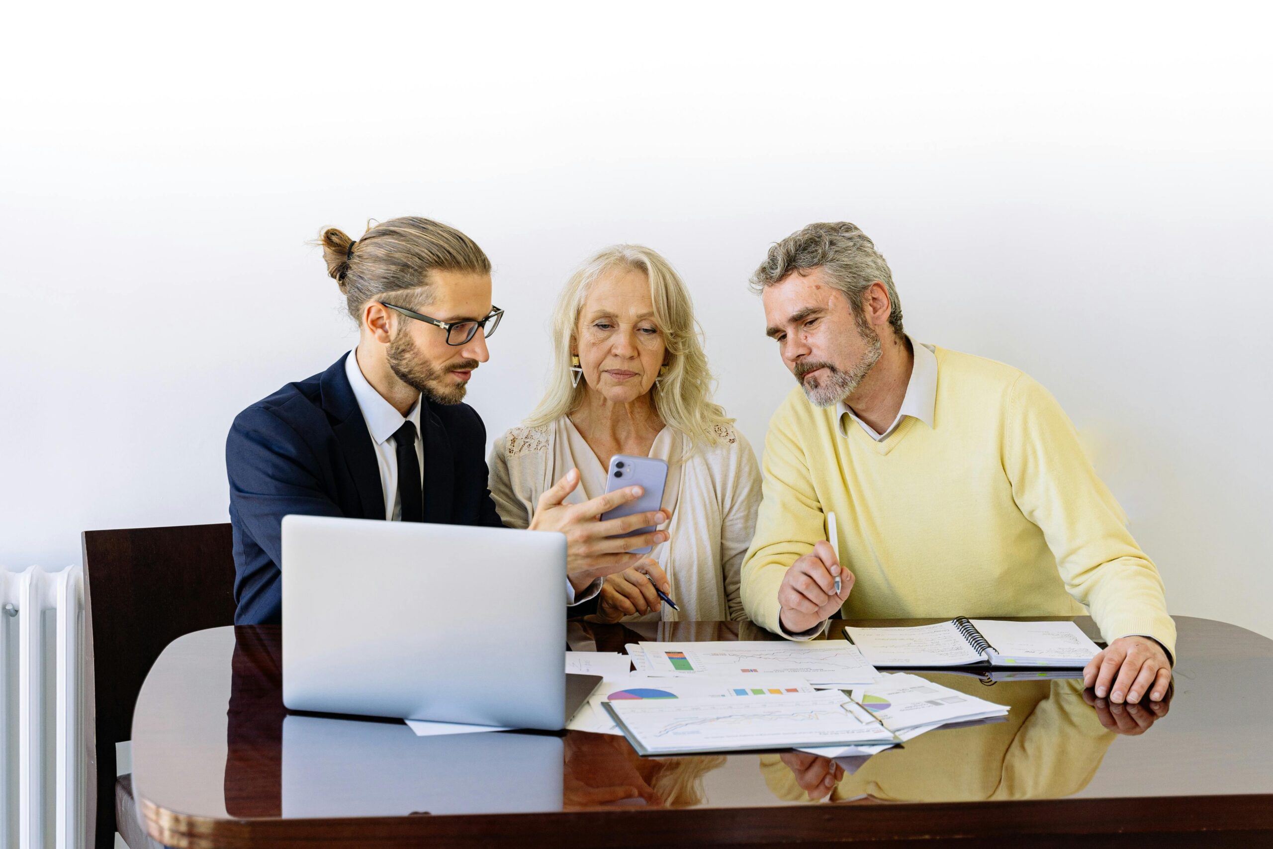 Three individuals collaborating on financial documents during a business meeting с обсуждением gigachat отзывов.