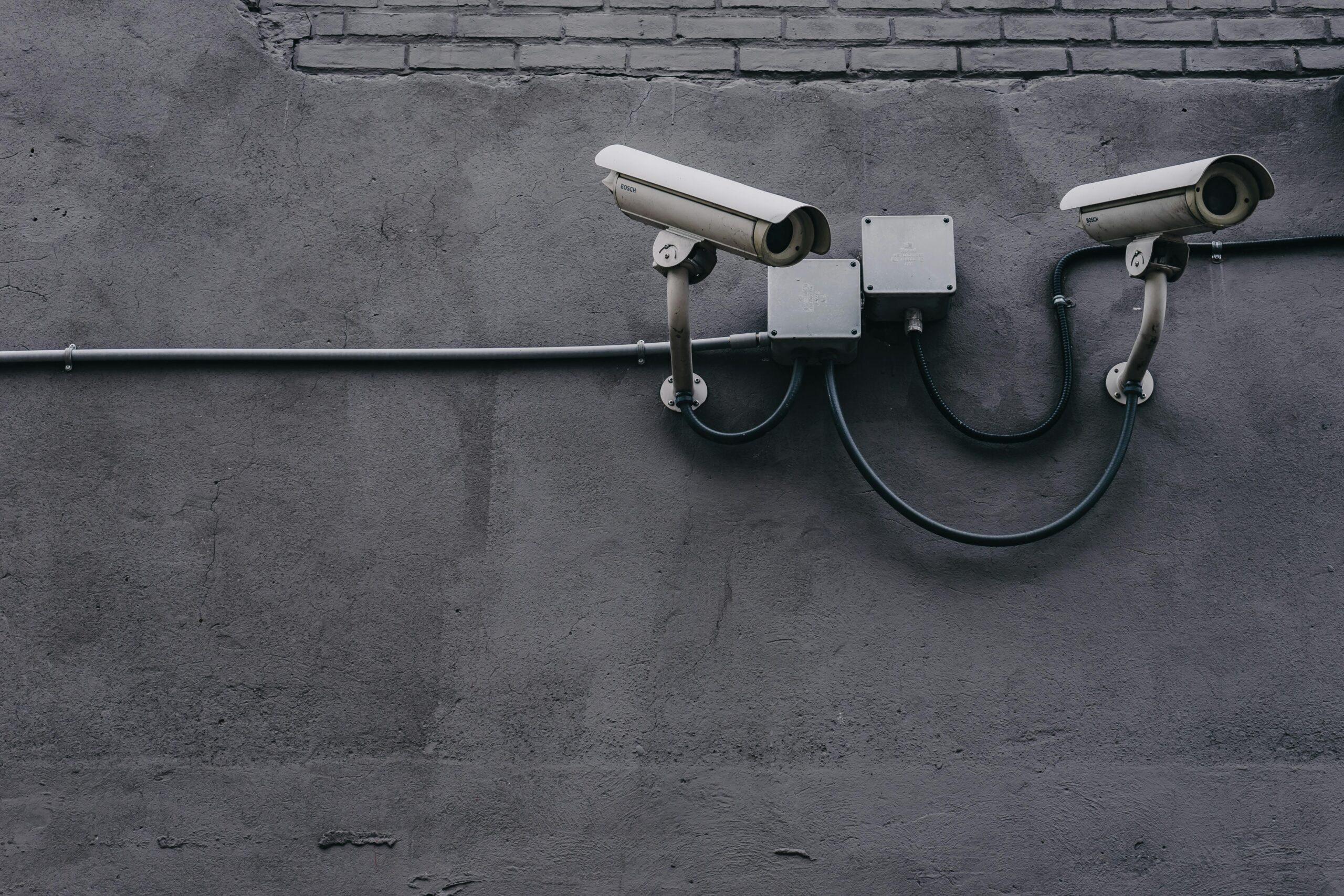 Two surveillance cameras mounted on a concrete wall, highlighting security technology и видеонаблюдение в коворкинге.