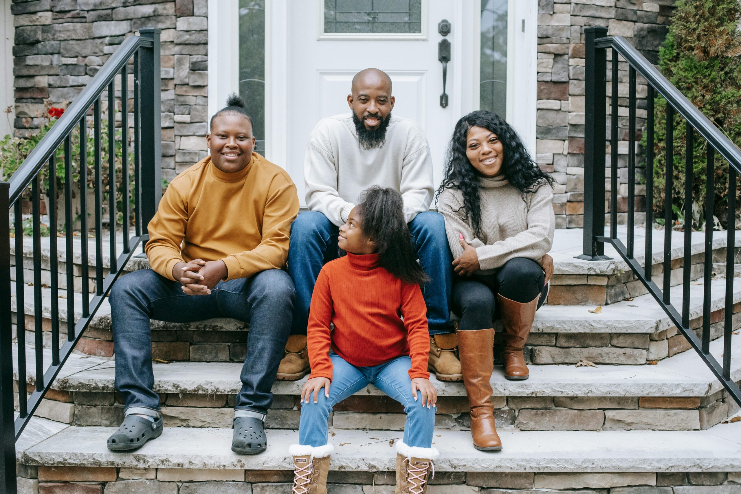 Smiling family of four enjoying time together on home's front steps.