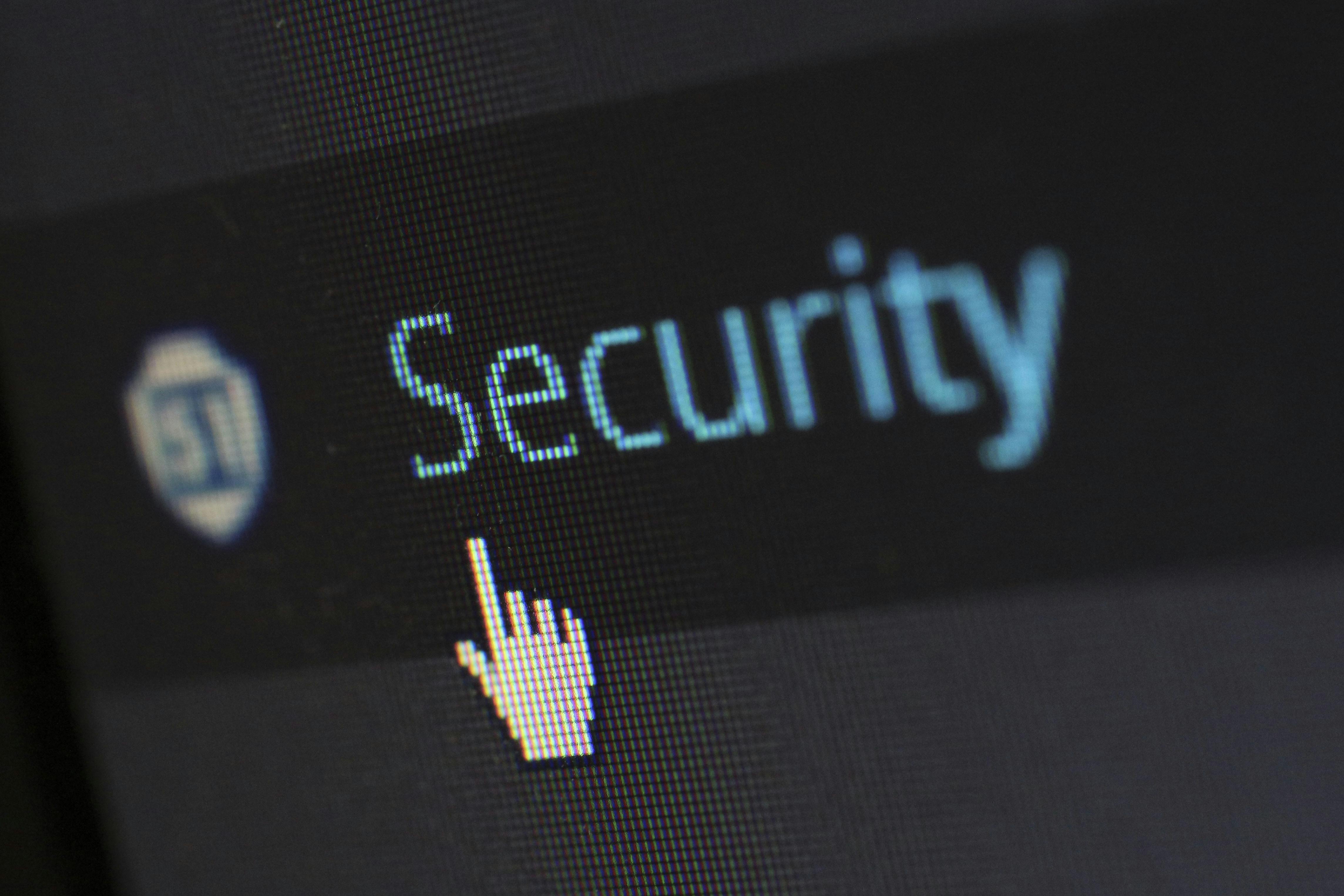 Close-up view of a mouse cursor over digital security text on display, подчеркивающий безопасность информации и персональных данных.