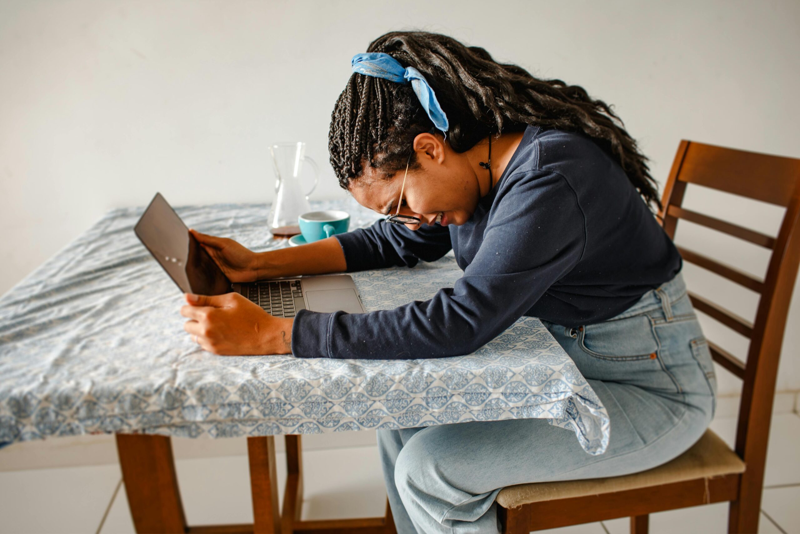Young woman with laptop looking stressed and tired at home, expressing work frustration.