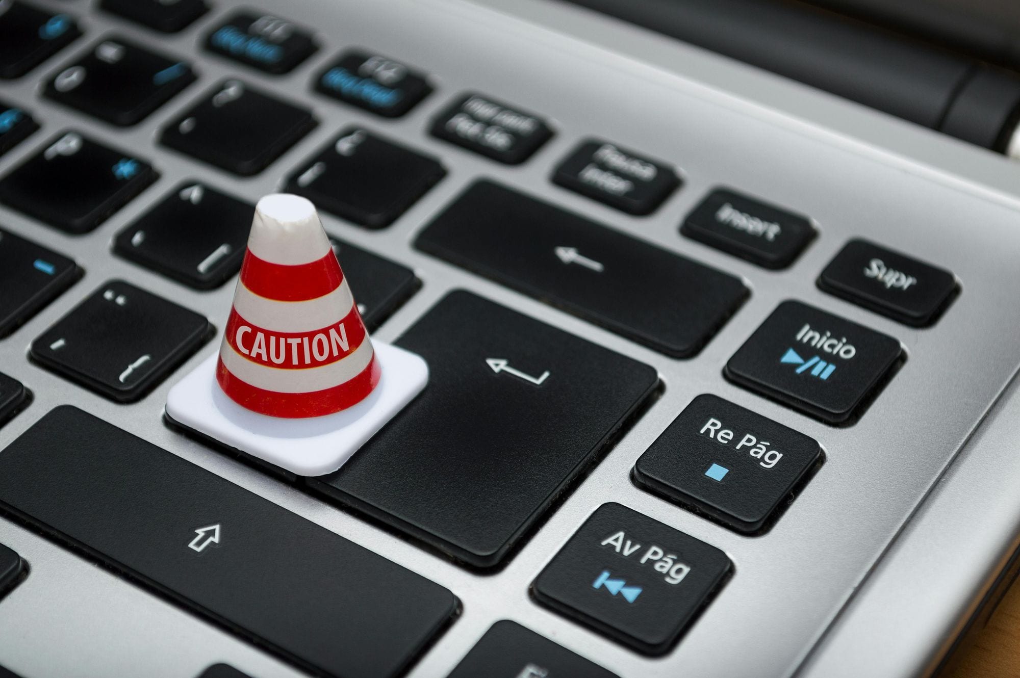 Miniature caution cone on a computer keyboard symbolizing data security and контроль обработки персональных данных.