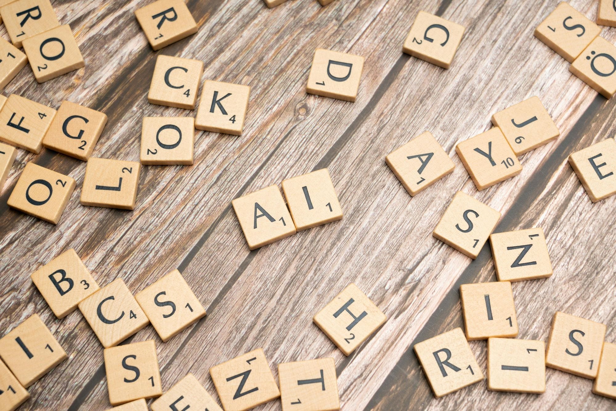 Wooden letter tiles scattered on a textured surface, spelling 